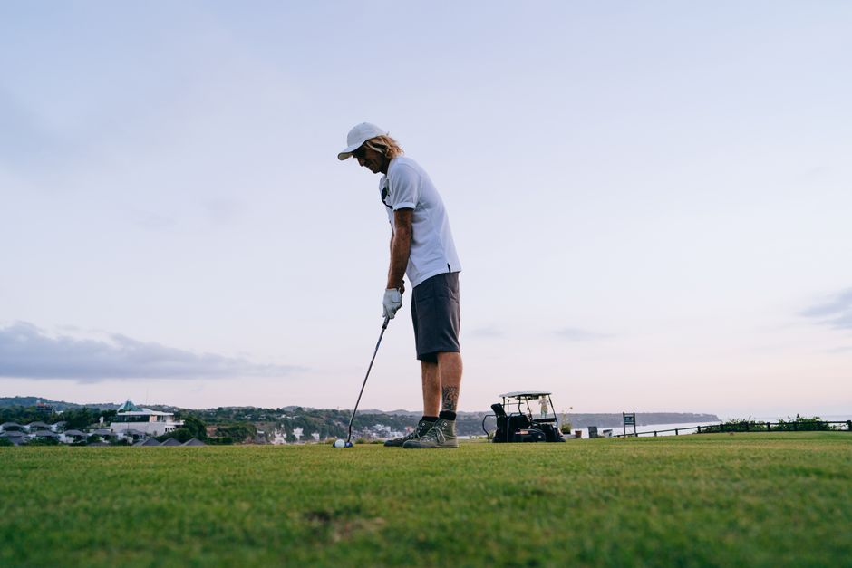 Man preparing to swing on a scenic golf course under a clear sky