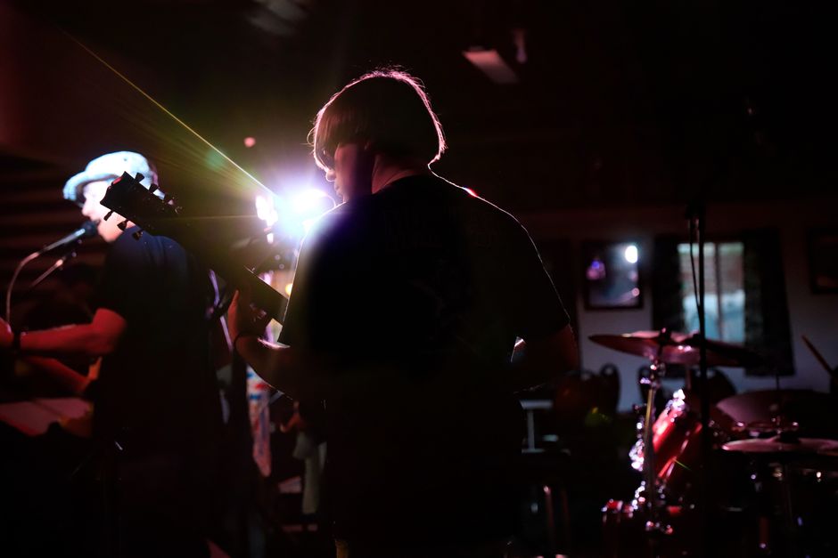 Silhouetted band performing live in a dimly lit venue, capturing the essence of live music.