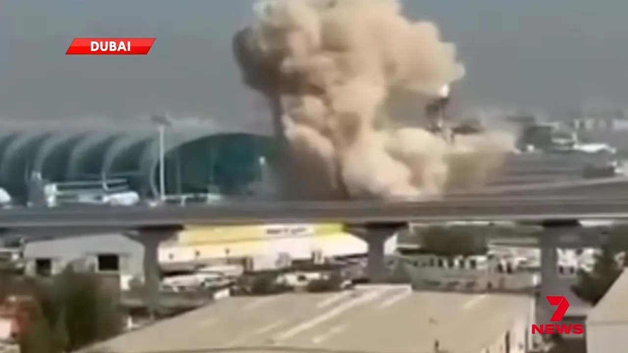 Close view of large smoke cloud rising beside Dubai International terminal with elevated road in foreground