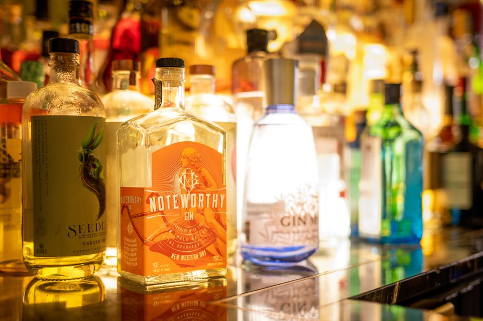 A colorful collection of gin bottles captured on a bar counter in warm lighting.