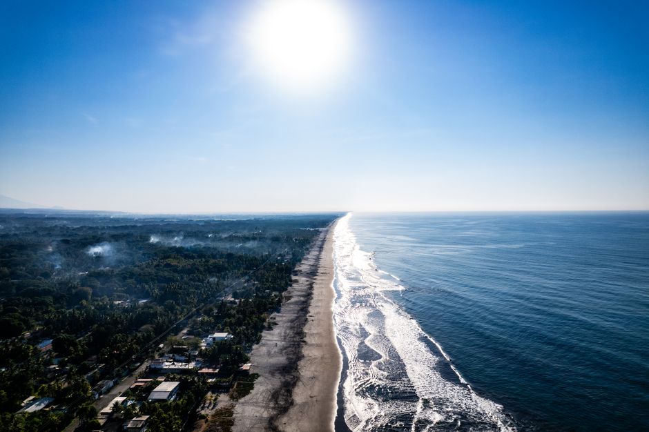 Breathtaking aerial view of sunlit beach and coastline in La Libertad, El Salvador.