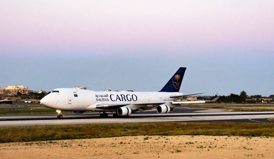 A Saudia Cargo plane on a runway at twilight with a serene sky background.