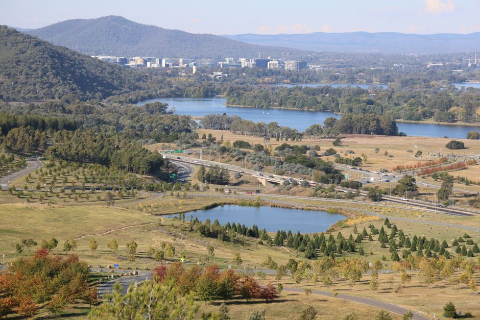 Scenic aerial shot of Canberra, showcasing lush greenery, lakes, and city skyline.