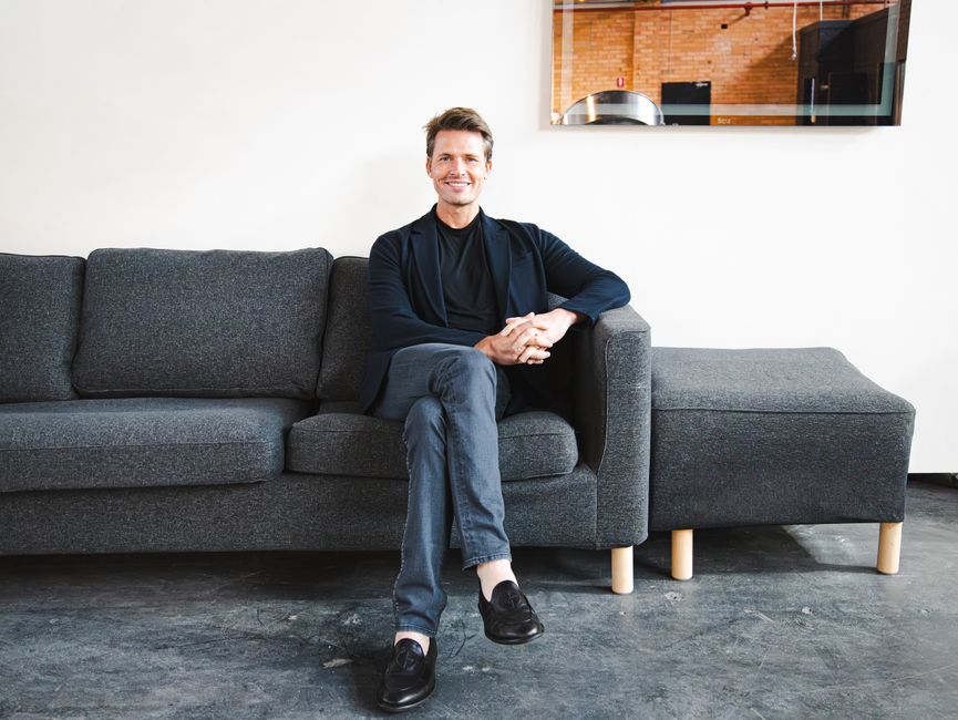 Confident entrepreneur seated on a couch in a modern office setting.