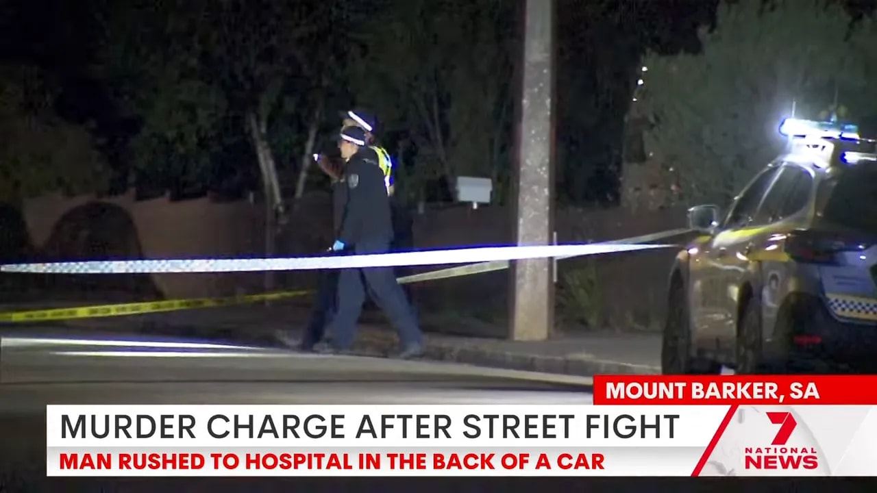 Police officers walking behind police tape at a cordoned-off Mount Barker street at night with a police vehicle nearby