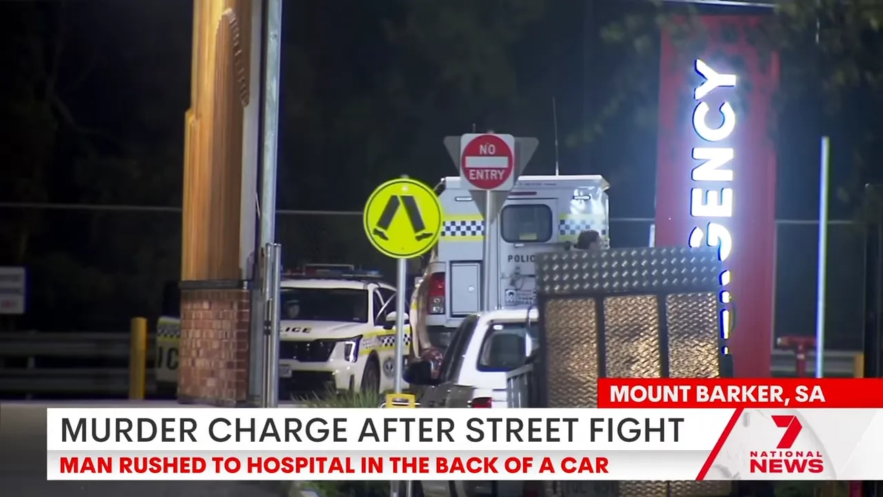 Police vehicles and an illuminated 'Emergency' sign outside a hospital at night
