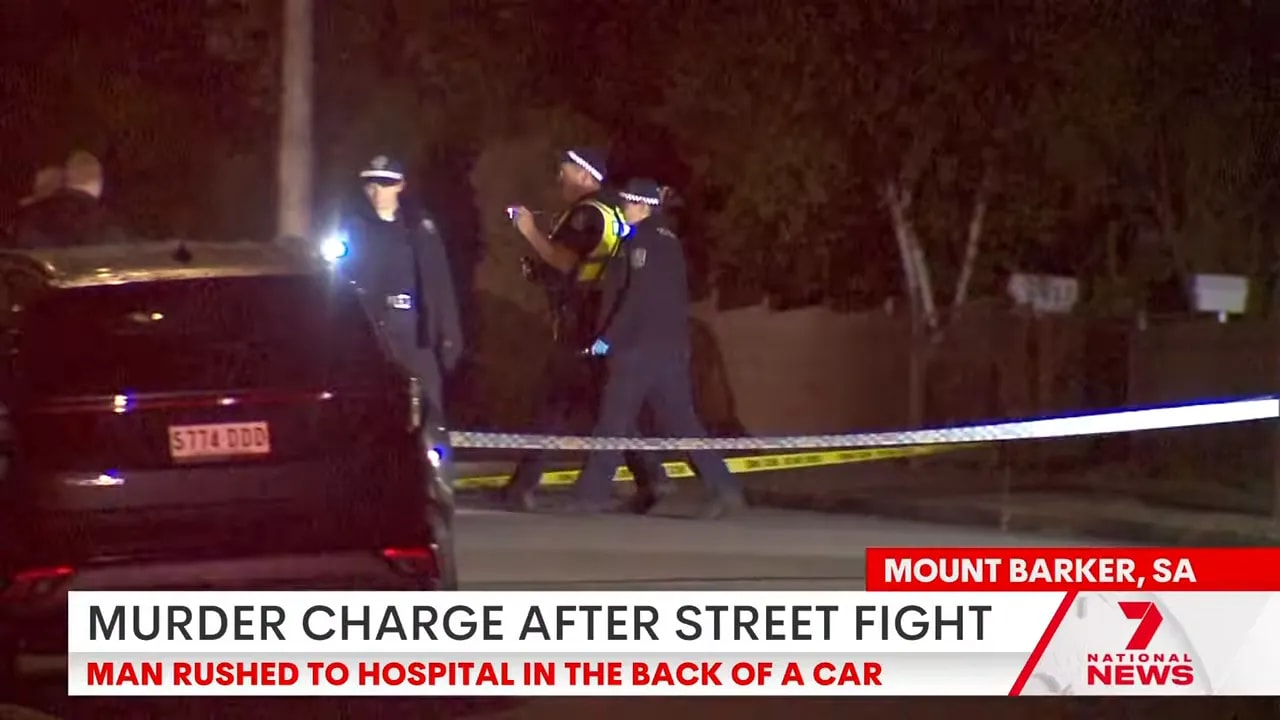 Police officers and crime scene tape at a residential street at night with a car parked nearby.