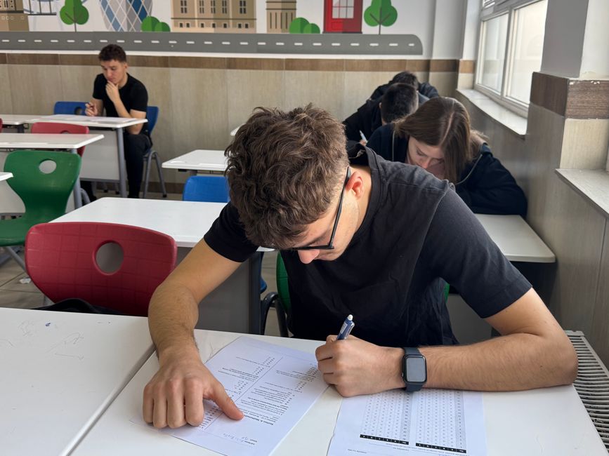 Students write exams in a classroom, focused on their tests. Educational exam setting.