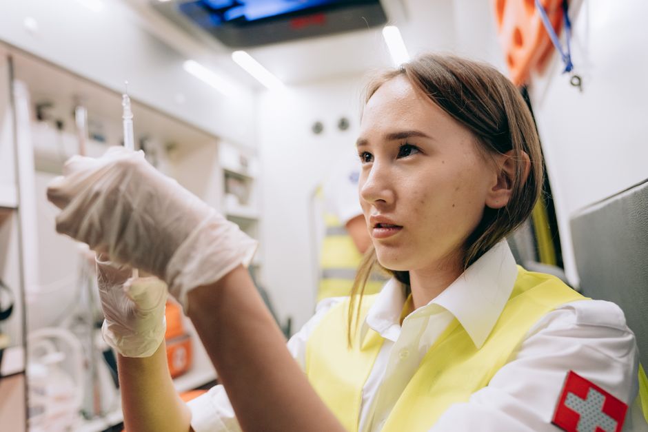 A focused paramedic prepares a syringe in an ambulance, showcasing emergency preparedness and healthcare professionalism.