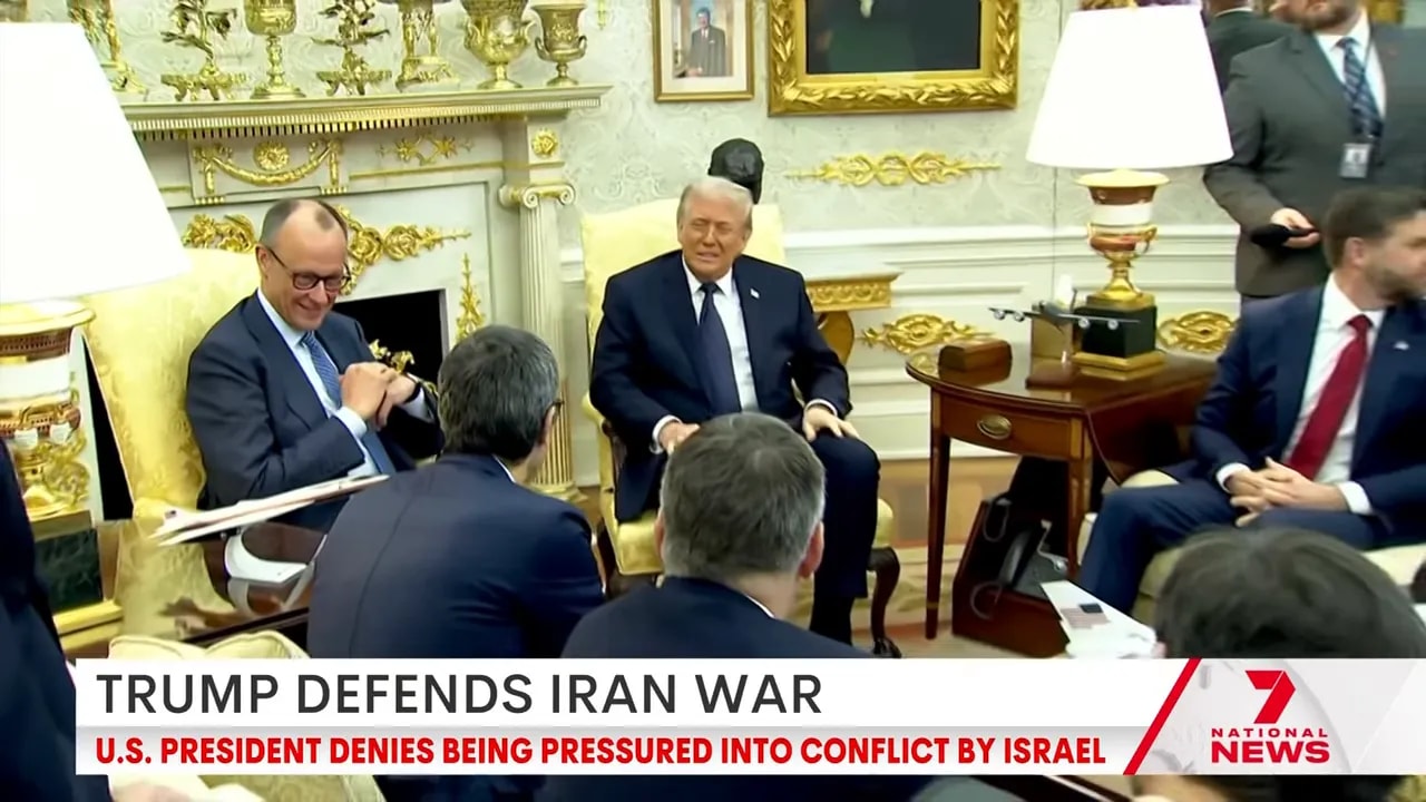 Wide view of an Oval Office meeting showing the president surrounded by advisers and staff