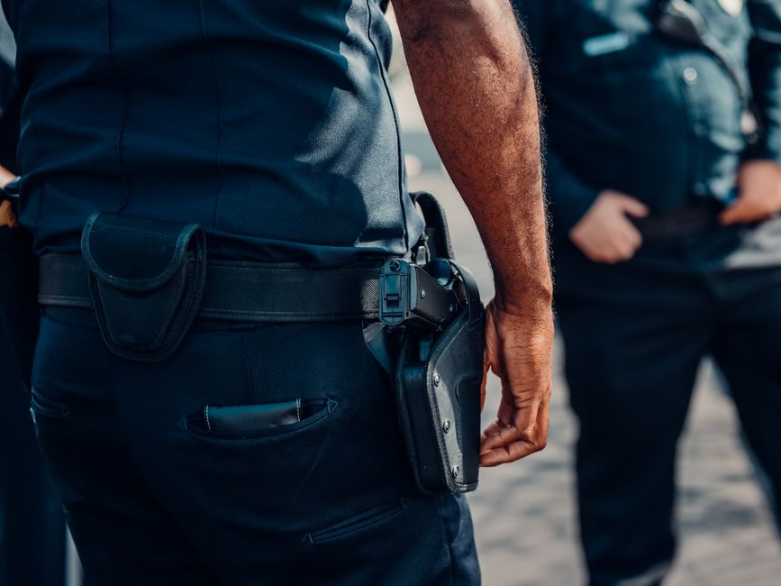 Close-up of a police officer's firearm securely holstered at the waist, conveying professionalism and readiness.