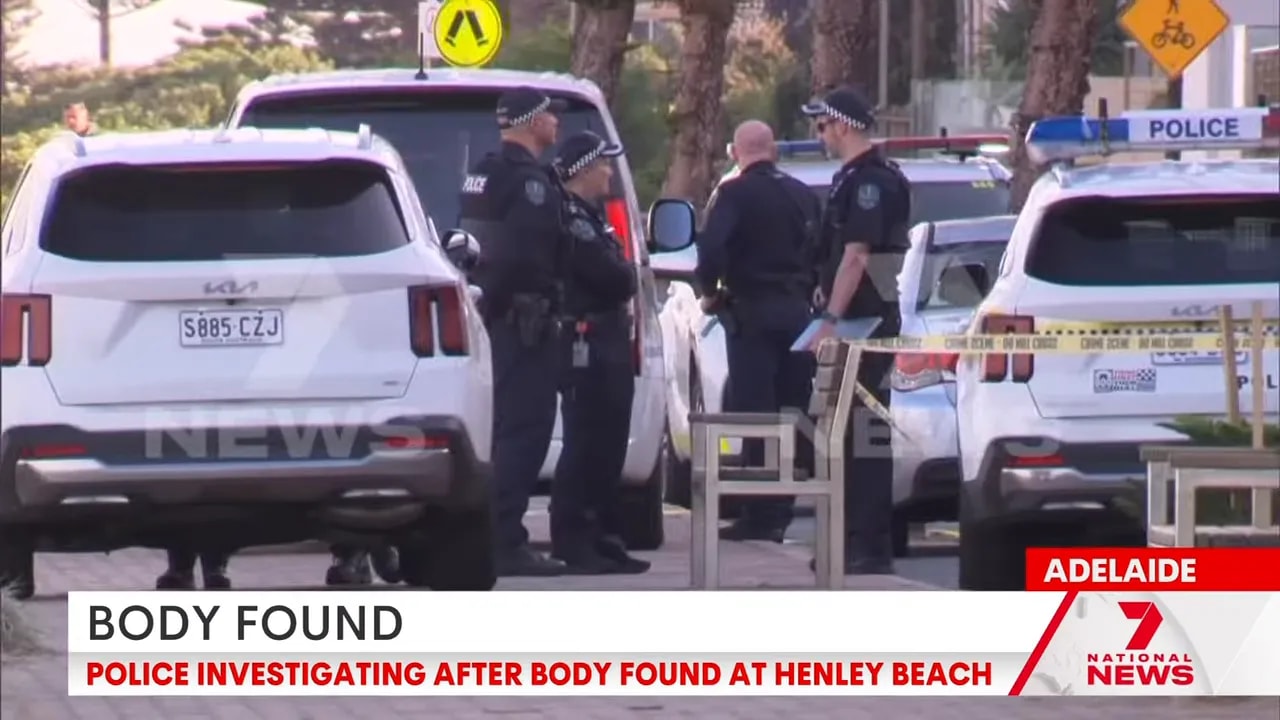Police vehicles and officers at Henley Beach apartment building after body found