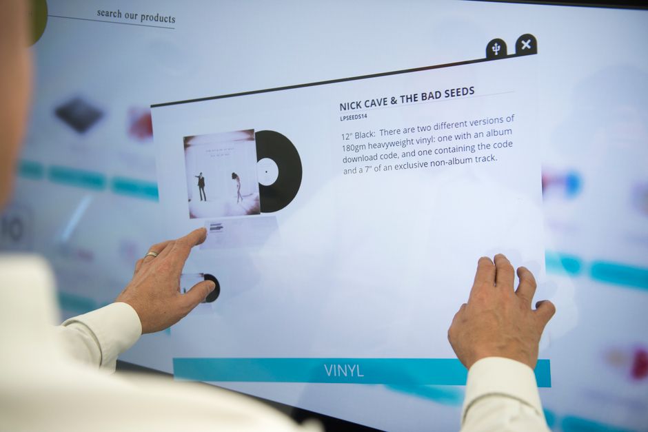 A person using a touchscreen to browse vinyl record information for Nick Cave & The Bad Seeds.
