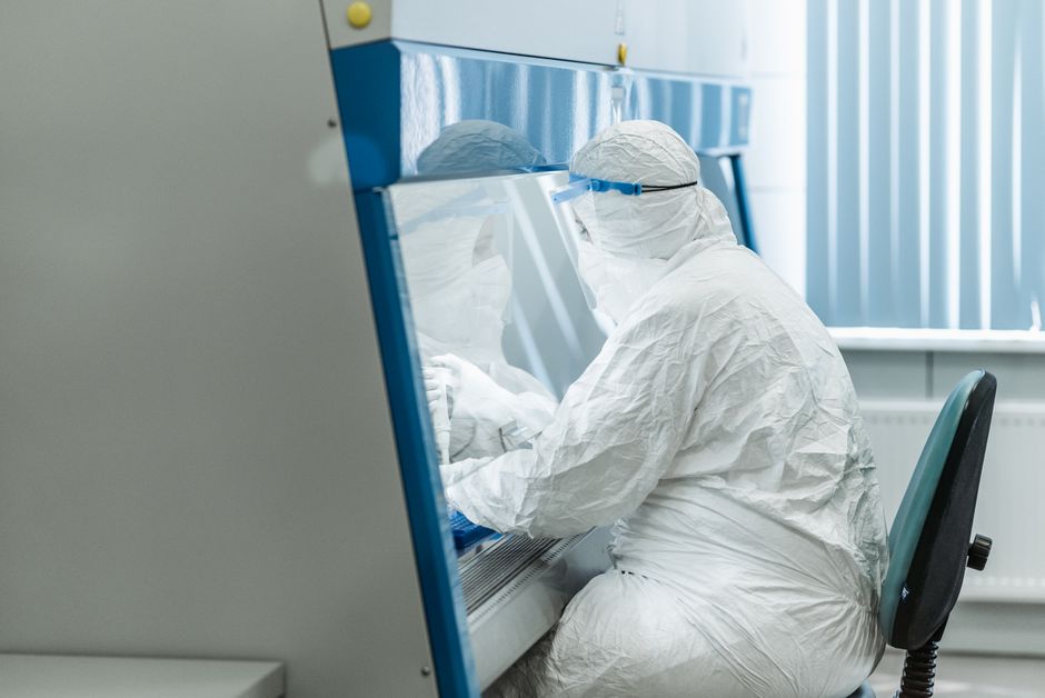 Researcher in protective gear working in a laboratory setting.