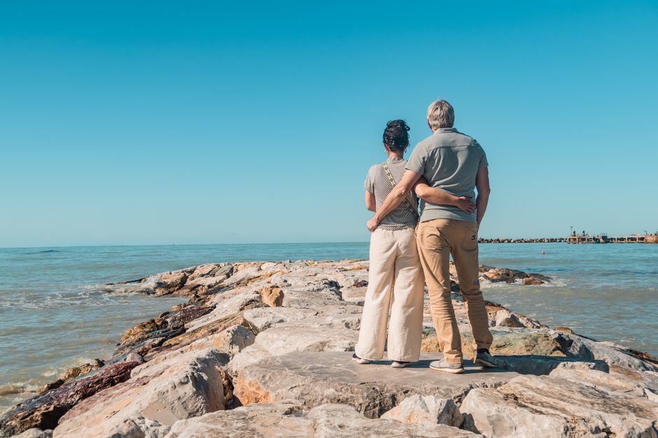 Romantic couple embracing, enjoying seaside view on rocky beach in Vada, Tuscany.