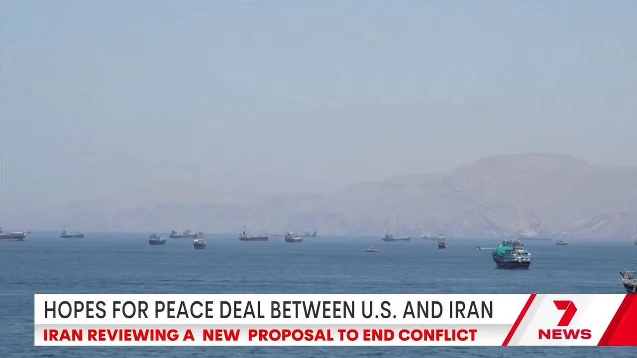 Multiple ships at sea with landmass in background in coverage of US-Iran peace deal hopes