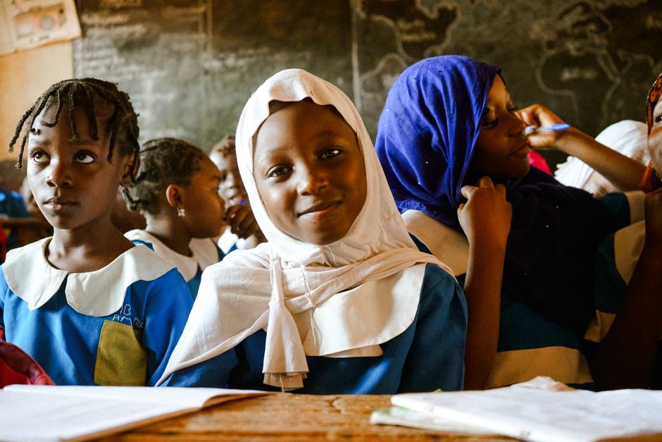 A vibrant classroom scene with smiling girls in school uniforms engaging in learning.