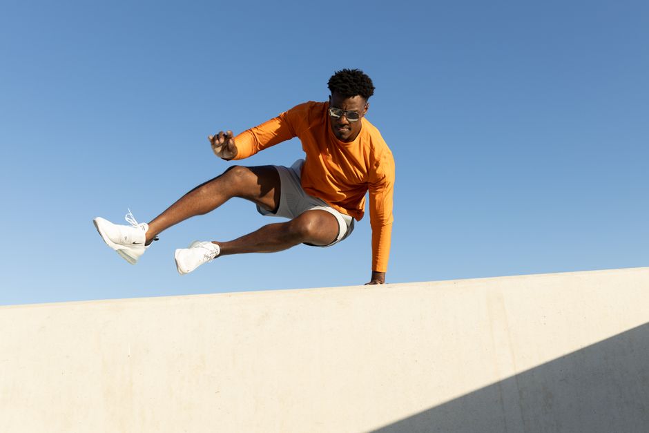 Man in athletic wear performs dynamic parkour move on a rooftop in Austin, Texas.