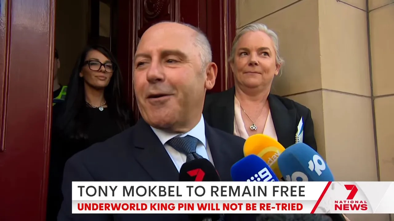 Tony Mokbel speaking into several news microphones on the courthouse steps, clear and well-lit